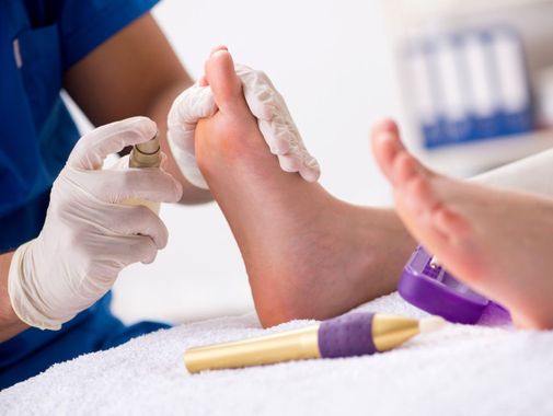 podóloga echando crema hidratante en los pies del paciente tras limar durezas