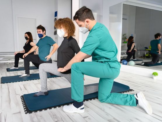 fisioterapeuta instruyendo a tres personas a hacer ejercicios de fortalecimiento de la cadera